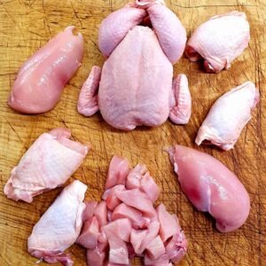 Fresh raw chicken whole and cut pieces including breast, wings, legs, and diced meat on butcher board – halal poultry for restaurants and catering suppliers.