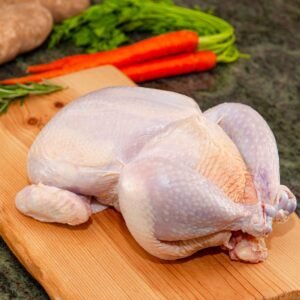Whole raw chicken on a wooden cutting board ready for cooking