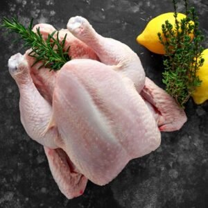 Whole raw chicken with fresh rosemary, thyme and lemon