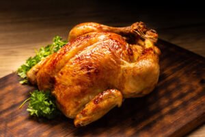 Roasted chicken with golden crispy skin served on a wooden board