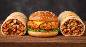 Two loaded chicken wraps and a crispy fried chicken burger with cheese, lettuce, and tomato arranged on a wooden surface.