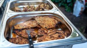 Grilled chicken fillets served in stainless steel catering trays for a halal food event